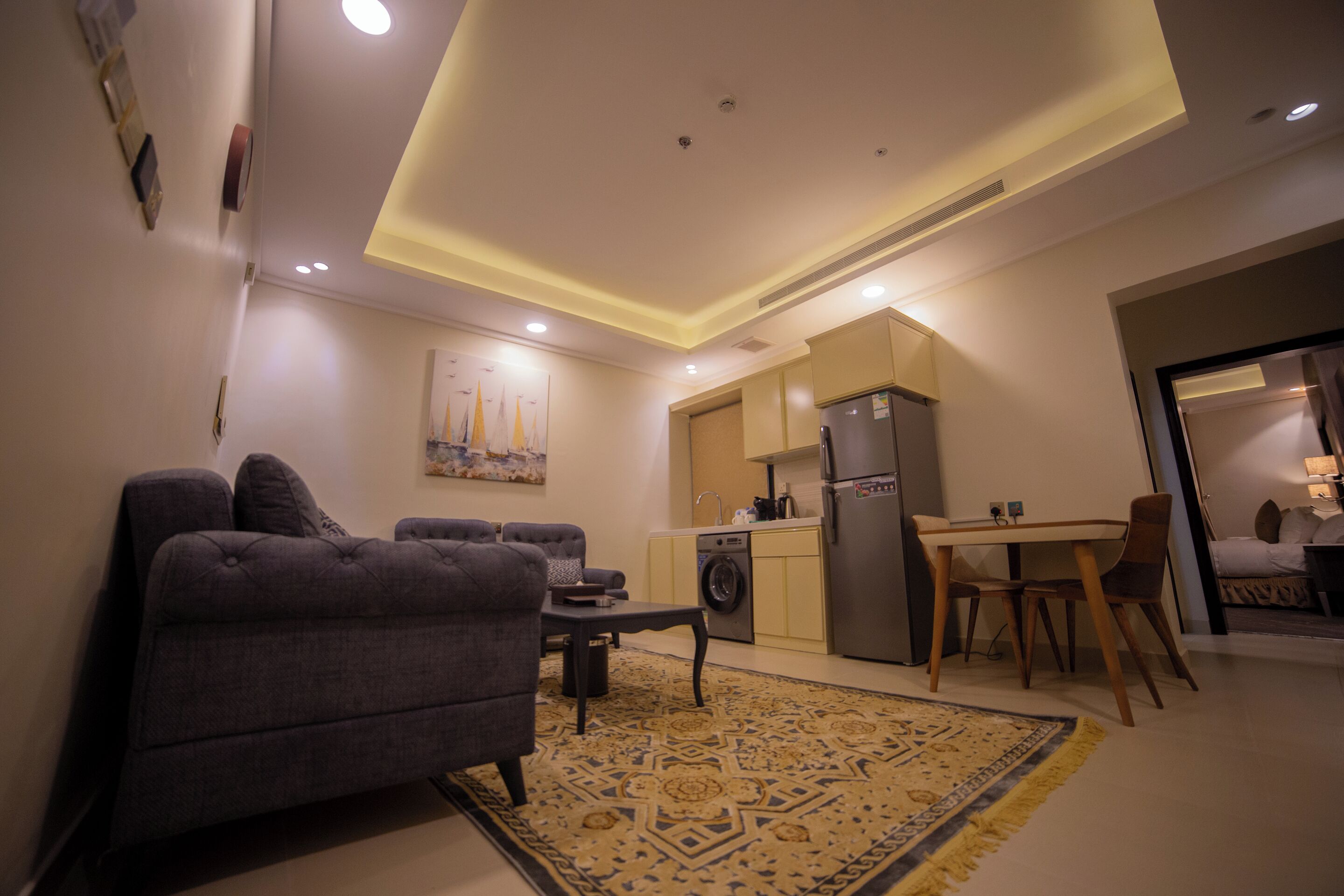 A compact living space with a sofa, a dining table, and a kitchen area including a washing machine.
