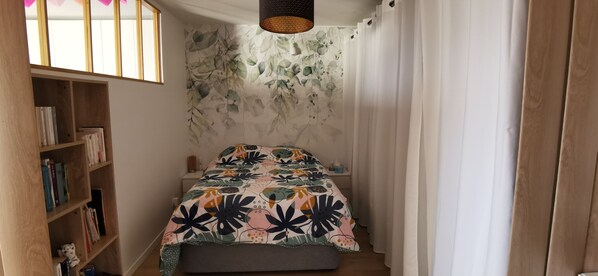 Une chambre à coucher avec un lit, une bibliothèque et un mur orné d’un motif végétal.