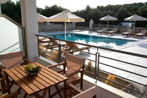 A poolside area with lounge chairs, umbrellas, and a table with a fruit bowl. - Michelangelo Suites and Apartments (Parga)