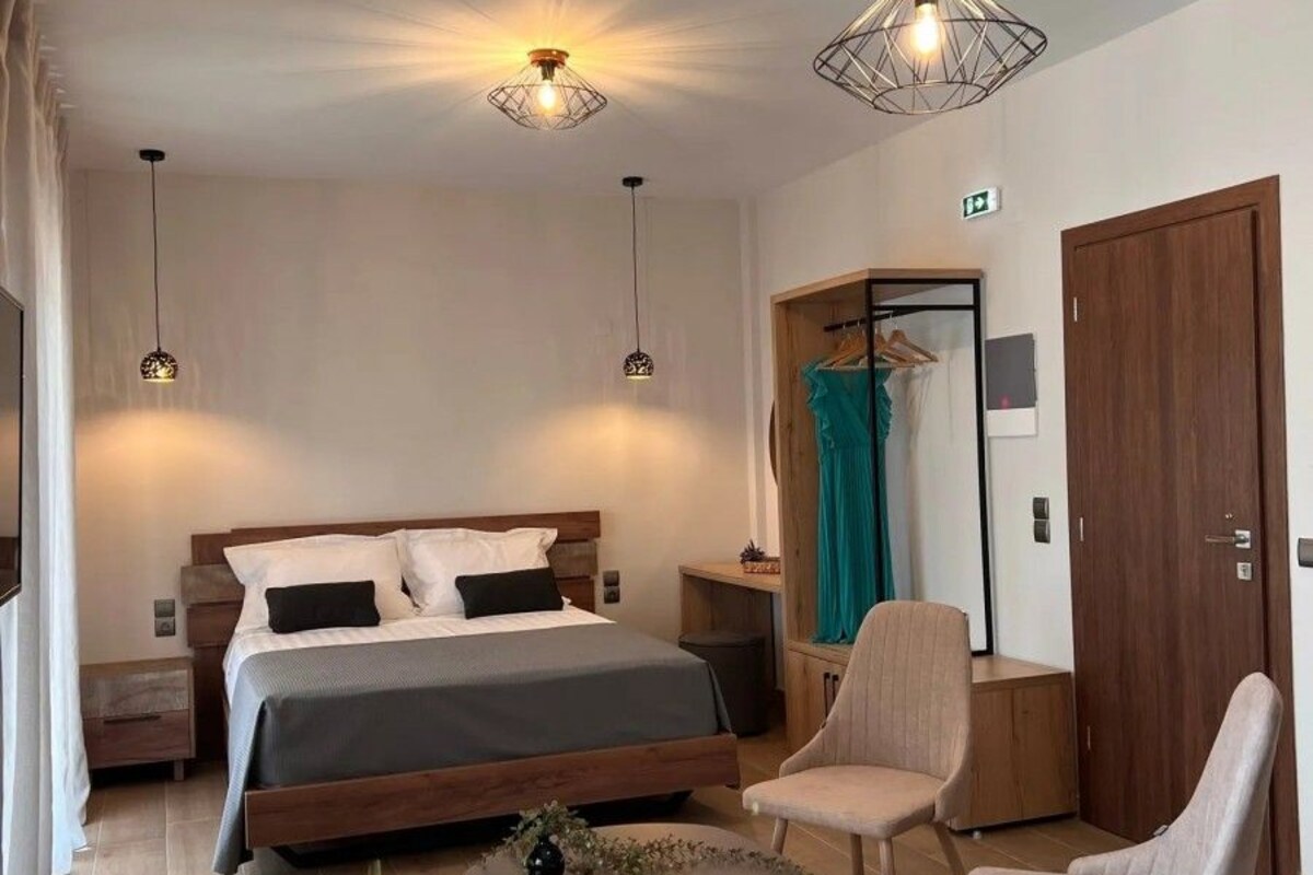 A modern hotel room with a large bed, a sitting area with a table, and two pendant lights.