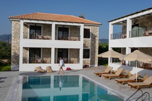 A two-story building with a pool, outdoor seating, and a clear view of the mountains. - Michelangelo Suites and Apartments (Parga)