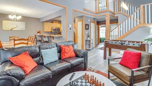 A spacious living room with a leather sofa, a coffee table with chess pieces, and a foosball table. - 'cozy Cove' Near Waterparks, Zip Line, Ski & More (Tannersville)