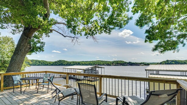 Eine Holzterrasse mit Gartenmöbeln mit Blick auf einen See.