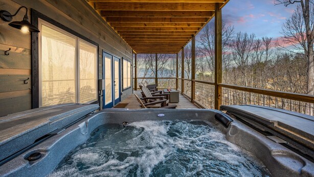Een hottubgedeelte met een houten terras, zitplaatsen en uitzicht op bomen.