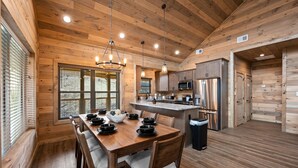 Een houten keuken in chaletstijl met een eettafel, stoelen en een centraal keukenblok.