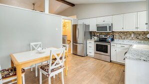 A modern kitchen with white cabinetry, a dining table with chairs, and a built-in oven. - Pet-friendly Fletcher Home - 13 Mi to Asheville! (Fletcher)