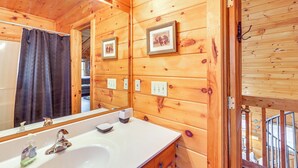 A wooden cabin bathroom with a large mirror, a sink, and a shower curtain. - Peaceful Cabin w/ Hot Tub: 11 Mi to Blue Ridge! (Epworth)