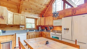 A wooden cabin kitchen with a large wooden table, wooden cabinets, a microwave, a stove, and a sink. - Peaceful Cabin w/ Hot Tub: 11 Mi to Blue Ridge! (Epworth)