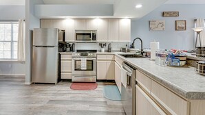 A modern kitchen with stainless steel appliances, wooden cabinets, and a granite countertop. - Updated Branson Condo w/ Lake Taneycomo Views! (Branson)