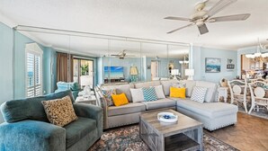 A spacious living room with a large sofa, a coffee table, and a ceiling fan. - Inlet Reef 515 2 Bedroom Condo by RedAwning (Destin)