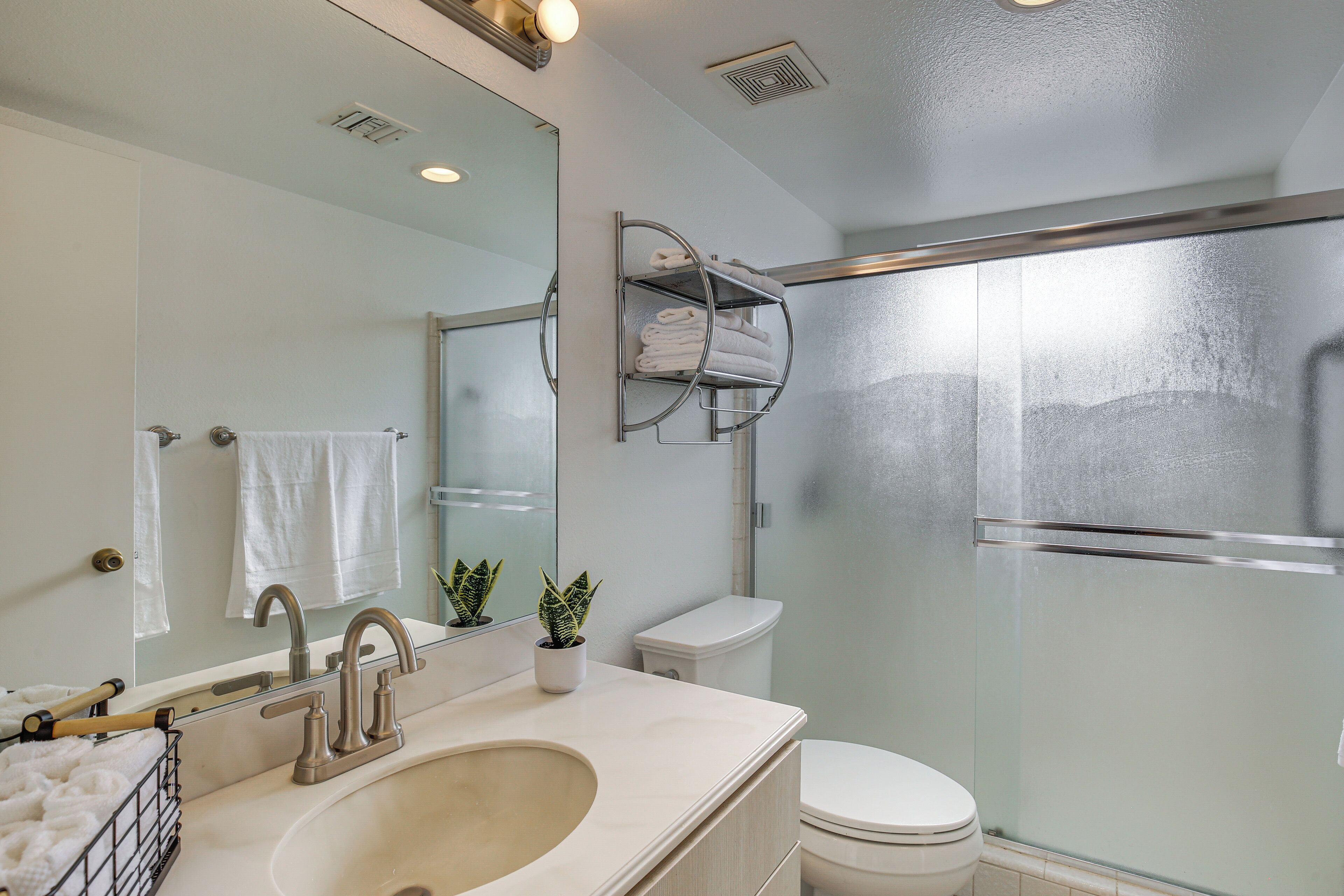 Un baño moderno con un lavabo grande, inodoro, cabina de ducha de vidrio y barra para toallas.