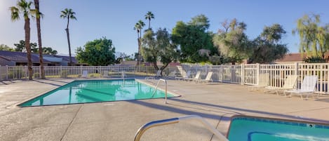 A swimming pool with a white fence and lounge chairs.