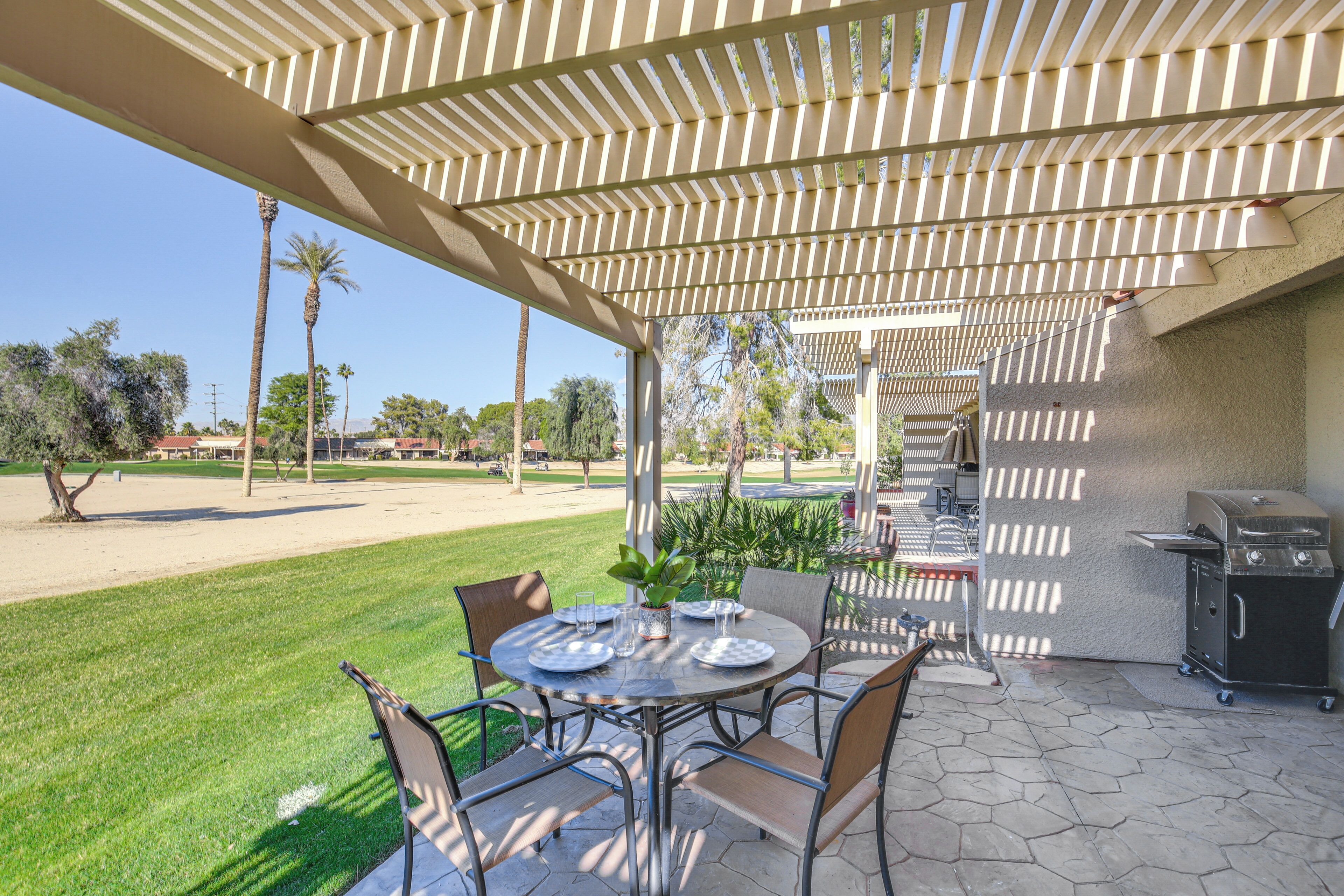 Une terrasse extérieure équipée d’un barbecue, de tables et de chaises.