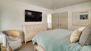 Une chambre à coucher avec un lit, une commode, un téléviseur et une porte.
