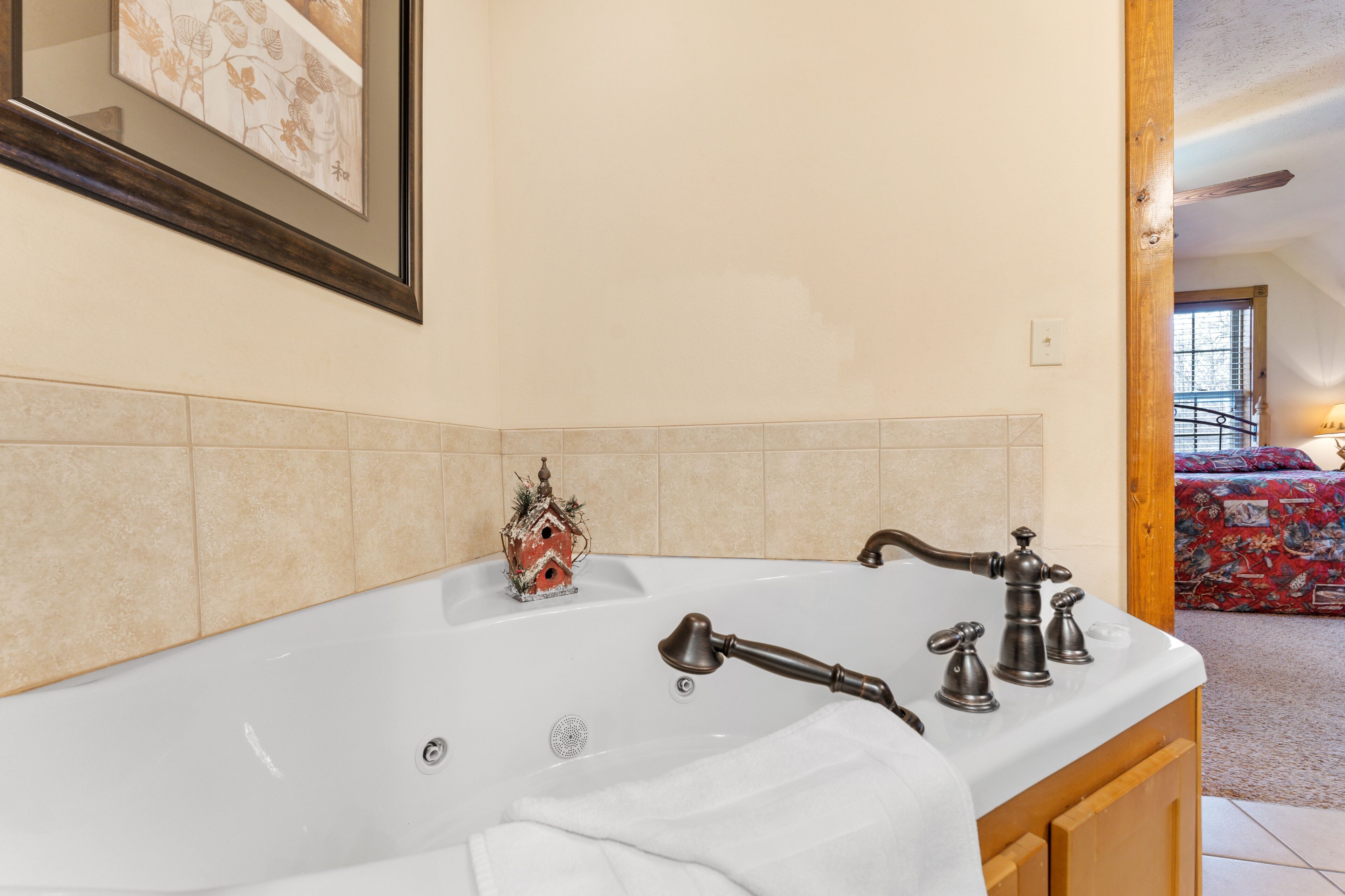 Un baño con una bañera, un armario de madera y una casa de pájaros decorativa.
