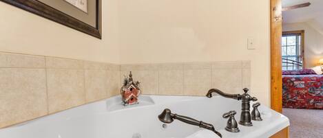 Un baño con una bañera, un armario de madera y una casa de pájaros decorativa.
