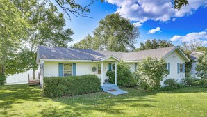 A single-story house with a front porch, a small front yard, and a clear blue sky.