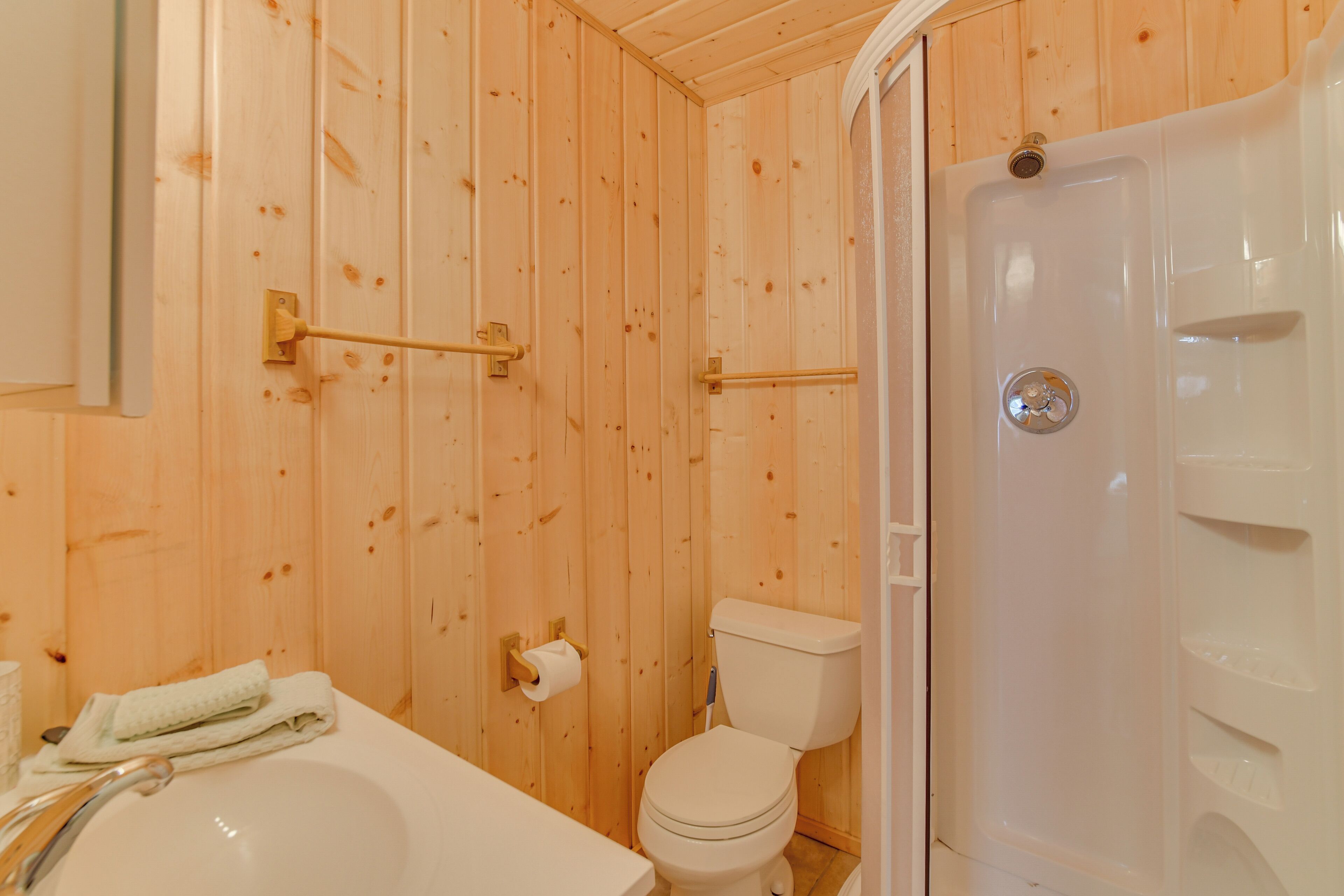 A wooden bathroom with a bathtub, toilet, and shower.