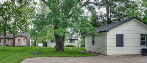 A single-story house with a front yard and a large tree.