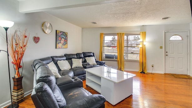 Ein Wohnzimmer mit einem schwarzen Ledersofa, einem weißen Couchtisch und einem Gemälde an der Wand.