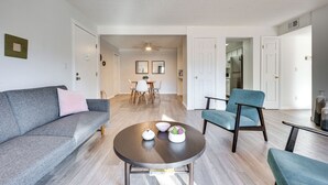 A modern living room with a grey sofa, a round coffee table, and a blue armchair.