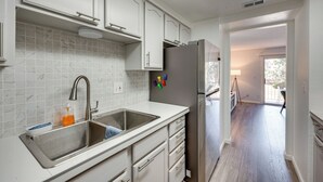 A modern kitchen with white cabinets, a stainless steel sink, and a refrigerator.