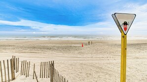 Une plage avec une clôture en bois et un panneau d’avertissement.