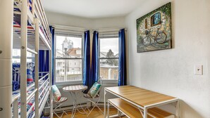 Une pièce avec des lits superposés, une table en bois, une chaise et une fenêtre avec des rideaux.