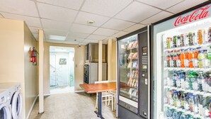 Un distributeur automatique orné du logo Coca-Cola, une table et un lave-linge, le tout installé dans un couloir.