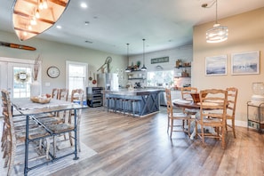 A spacious kitchen with a central island, wooden chairs, and a dining table.
