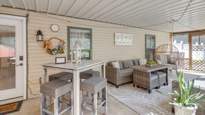 Une véranda couverte, aménagée avec des meubles en osier, une table et une chaise.