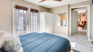 Une chambre à coucher avec un lit, un ventilateur de plafond et une porte donnant sur une autre pièce.