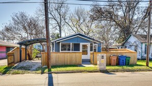 Une maison d’habitation avec un toit bleu, une clôture en bois et une véranda couverte.