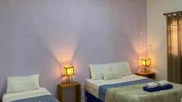 Habitación de hotel con dos camas, ventilador de techo, aire acondicionado y ventana con cortinas.