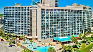 Um hotel grande com vários andares, piscina e áreas de estar ao ar livre.