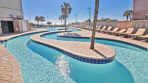 Piscina com design curvo, rodeada por espreguiçadeiras e palmeiras.