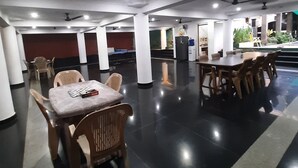 A spacious indoor area with multiple tables and chairs, ceiling fans, and a water dispenser. - Villa Serenity Le Sejour with Swimming Pool (Puducherry)