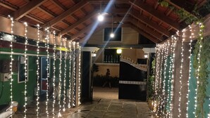 An indoor corridor with a tiled floor, wooden ceiling beams, and string lights. - Villa Serenity Le Sejour with Swimming Pool (Puducherry)