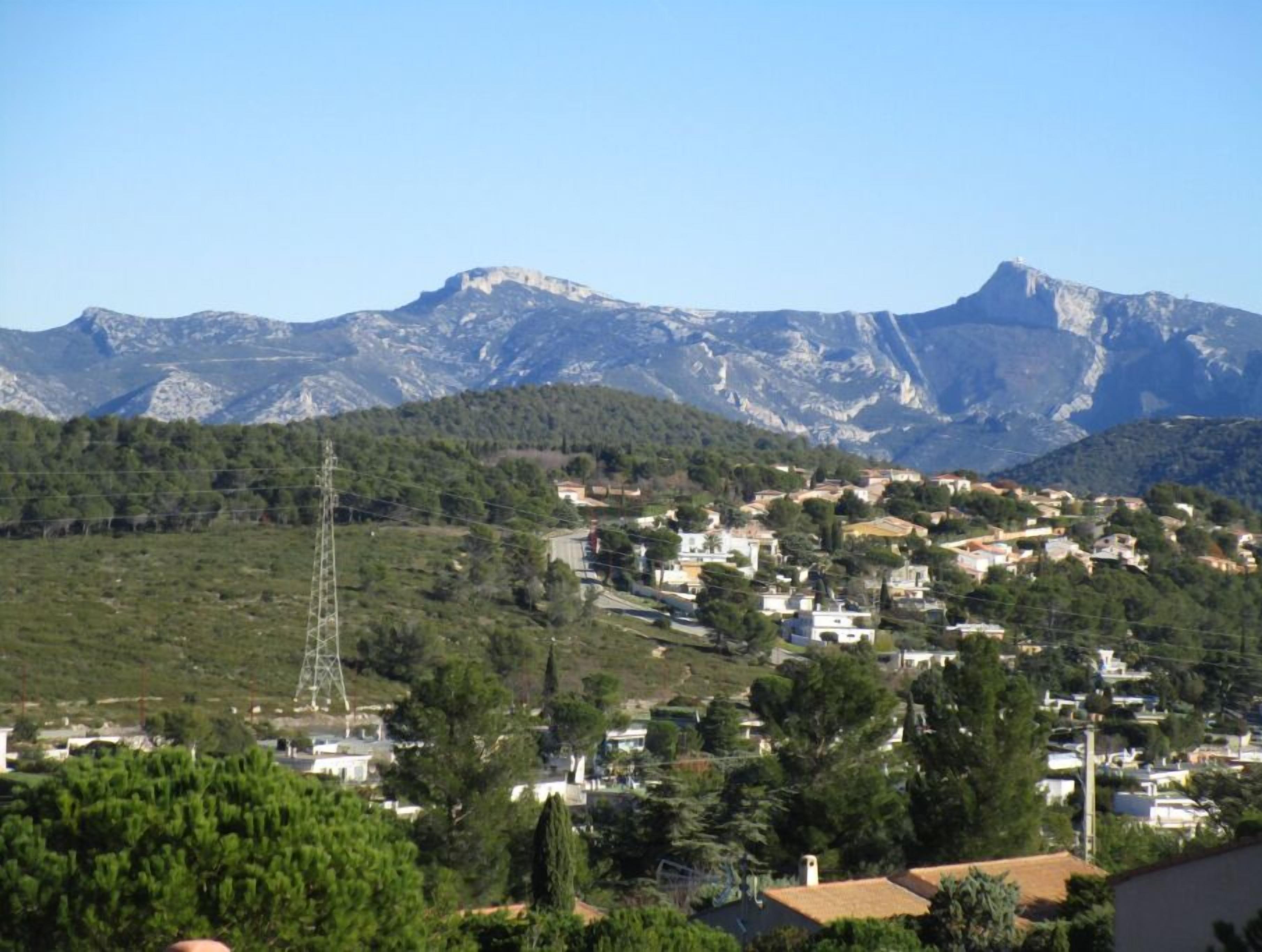 A hillside town with houses and a power line tower.