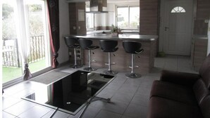 Una cocina moderna con una isla central, taburetes de bar y un comedor.