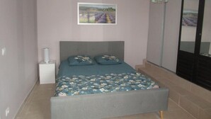 Un dormitorio con cama, mesita de noche, un cuadro en la pared y una puerta corredera.