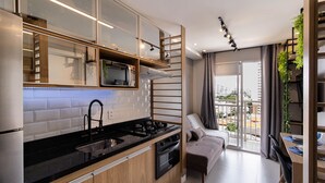 Une cuisine moderne avec un plan de travail noir, des appareils en acier inoxydable et des meubles de rangement en bois.