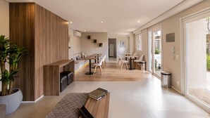Un intérieur moderne agrémenté d’un mur d’accent en bois, d’un coin salon avec un banc et d’un espace repas avec des tables et des chaises.