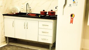 A compact kitchen with a refrigerator, stove, and a microwave. - Flat Jaguanum (Mangaratiba)