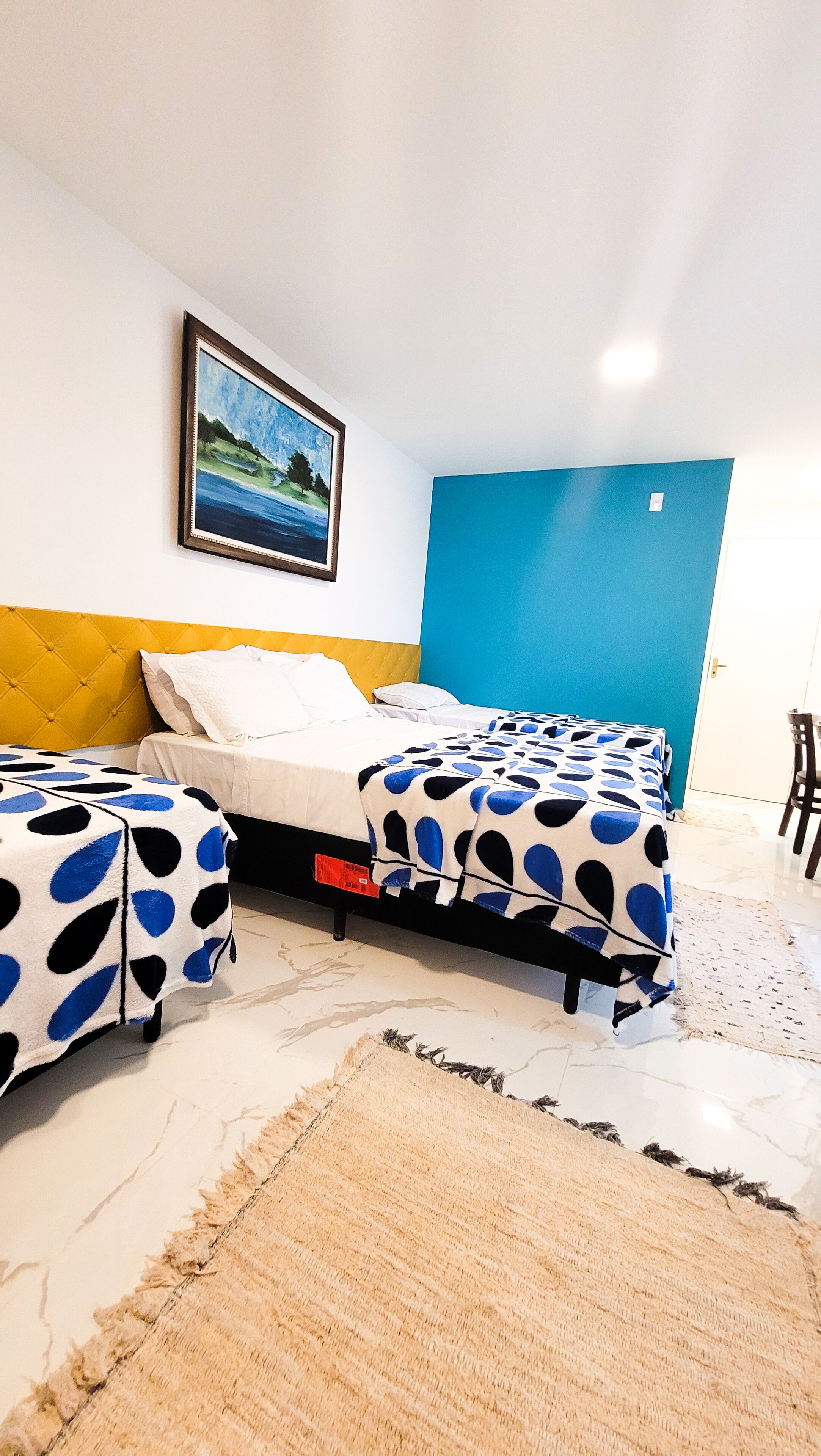 Un dormitorio con dos camas, un cuadro y una pared azul.