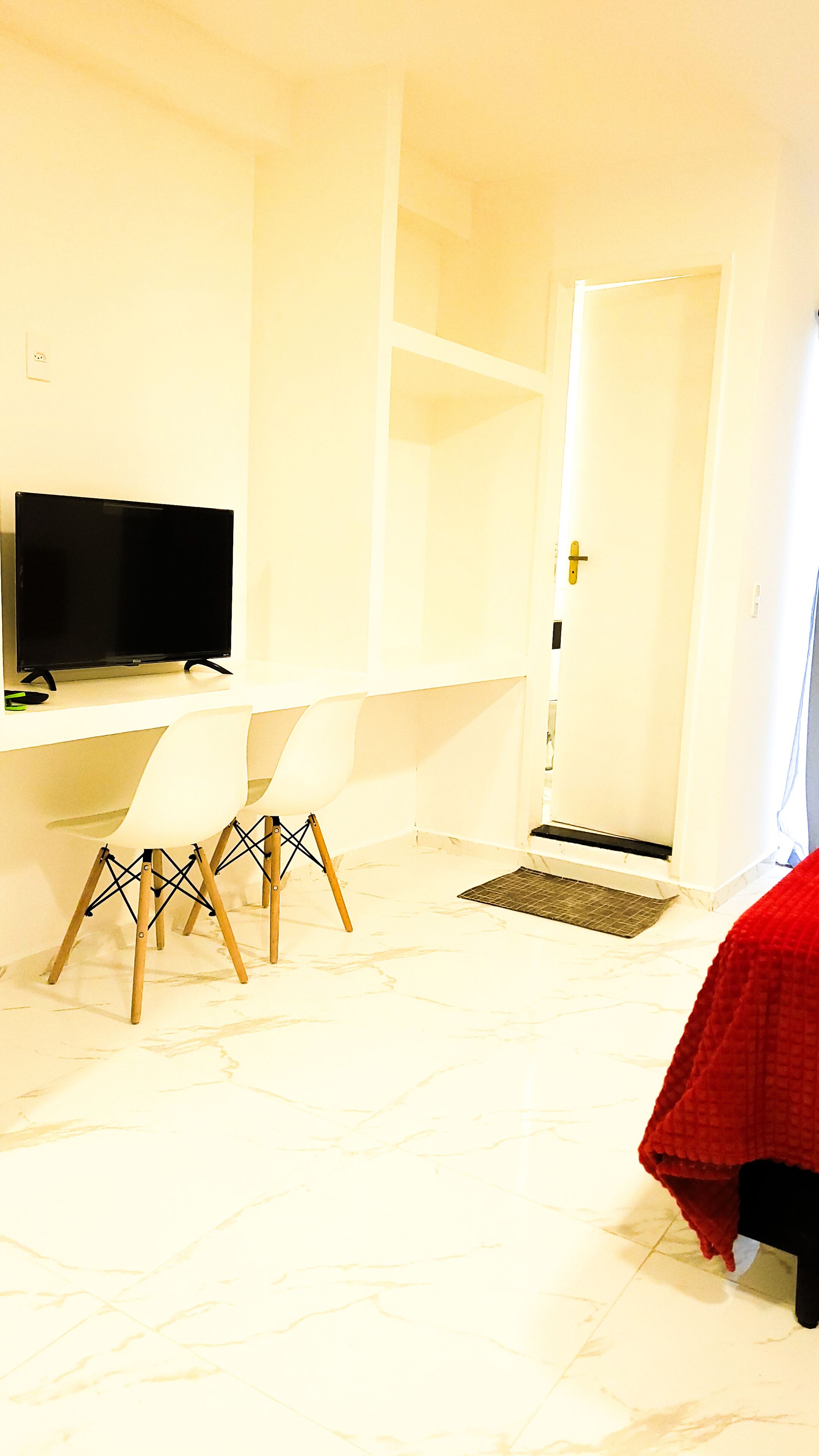 A room with a desk, a chair, a television, and a door.