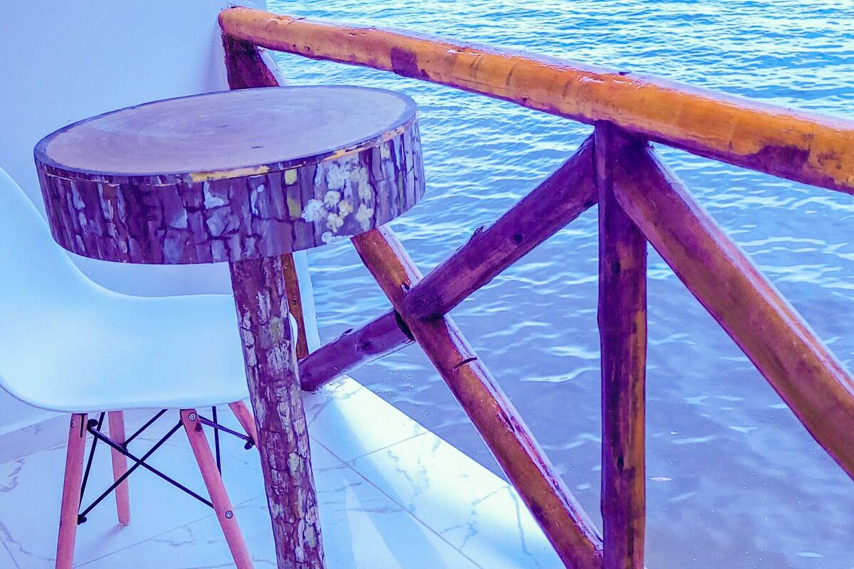 Een terras met een ronde tafel en twee witte stoelen, met uitzicht op een wateroppervlak.