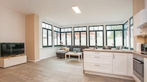 A modern kitchen with a dining area, large windows, and a flat-screen TV. - Residenz zum Südstrand - Klappke (Borkum)