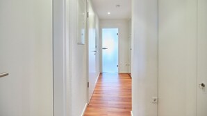 A narrow hallway with white walls and wooden flooring, leading to a door at the end. - Villa Wilhelmine - Klein-wiebke (Borkum)