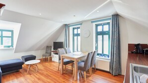A modern, well-lit room with a dining table, chairs, a sofa, and a television. - Villa Wilhelmine - Klein-wiebke (Borkum)